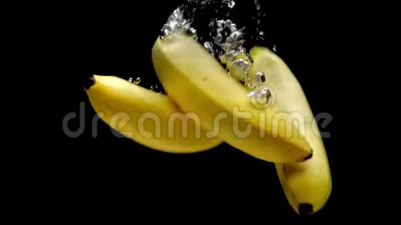 三根黄色香蕉在黑色背景下落入透明水视频的预览图