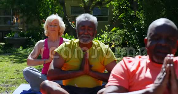 积极参加混合种族活动的老年人在养老院花园里练习瑜伽的正面景色视频的预览图