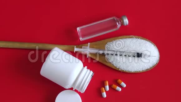 胰岛素注射器放在木勺上糖和药片放在红色背景上视频的预览图
