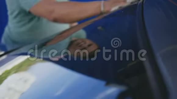 一个男人在洗车时用白色毛巾擦拭一辆车视频的预览图