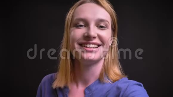 白种人金发女人穿着衬衫在黑色背景下使用智能手机制作自拍照片的自我视频视频的预览图