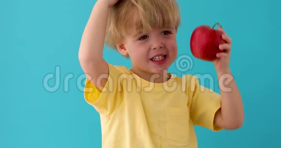 带着红色美味苹果的孩子在蓝色背景上视频的预览图