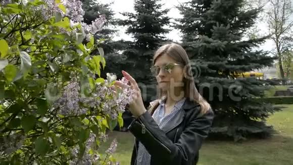 春天的花园里女孩闻到了丁香树的花香视频的预览图