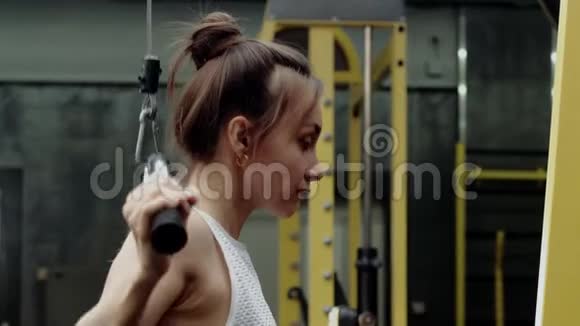 年轻女性健身模型练习手臂和背部肌肉的重量视频的预览图