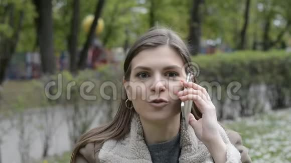 愤怒迷人的女孩在城市公园里用电话谈论大自然视频的预览图
