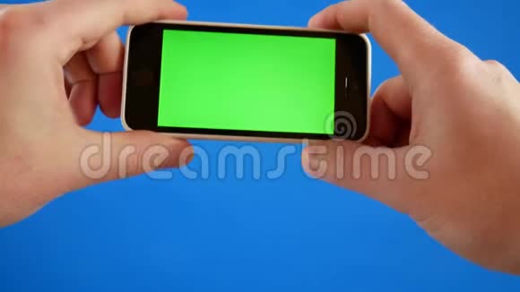 手拿着智能手机玩游戏智能手机蓝色背景与绿色屏幕色度游戏概念视频的预览图
