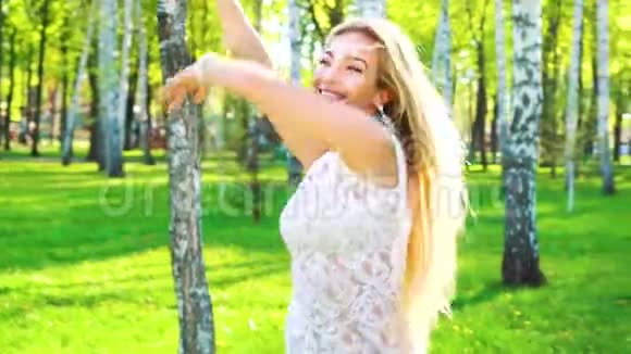 阳光照耀着穿着迷人服装在桦树林跳舞的快乐年轻女子视频的预览图