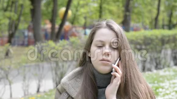 城市游乐园里一位年轻美女的智能手机上的情感对话视频的预览图