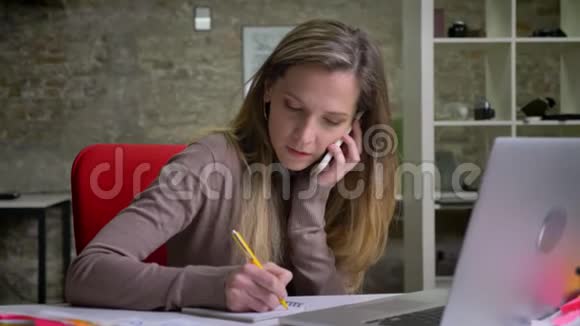 忙碌的白种人女员工在电话中交谈并在旁边预约视频的预览图