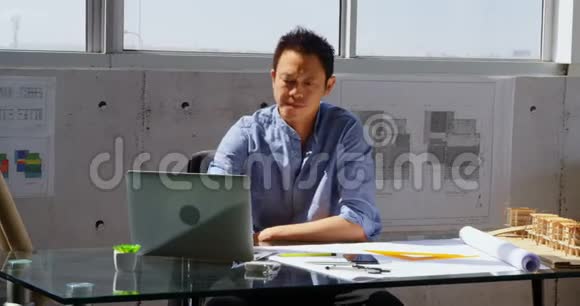 亚洲男性建筑师使用笔记本电脑在一个现代化的办公室4k视频的预览图