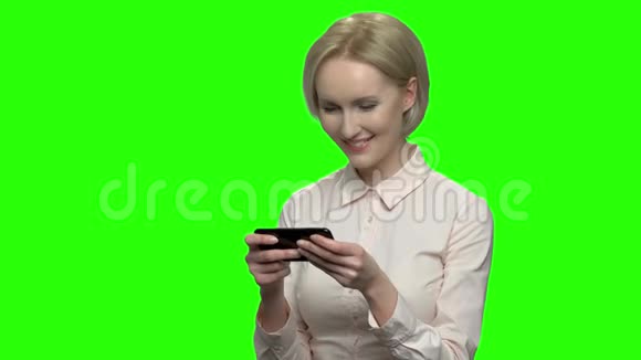 漂亮的商务女性在她的智能手机上玩游戏视频的预览图