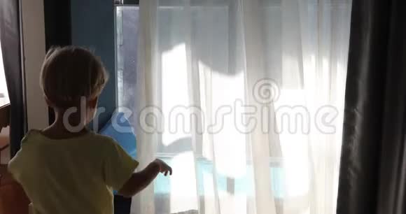 房间里窗帘后面的小男孩视频的预览图