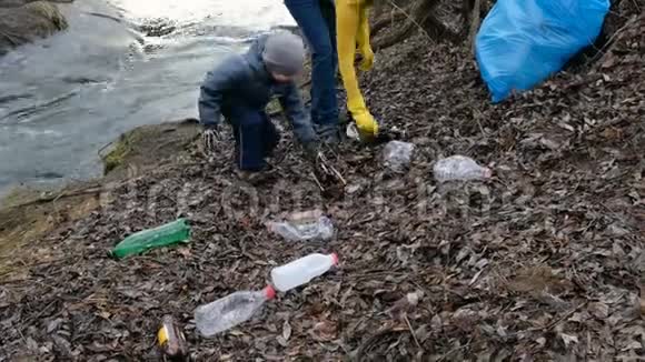 女志愿者带着她的孩子清理河边的垃圾生态和环境概念视频的预览图
