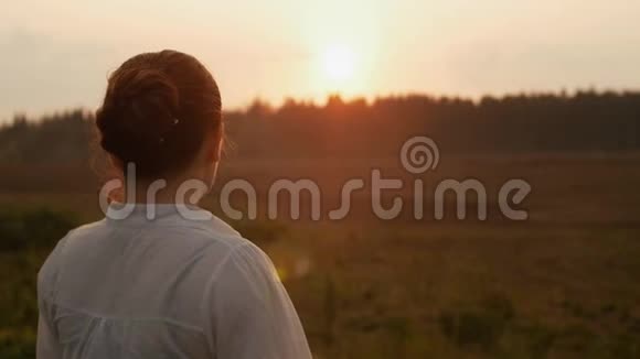 穿着白衬衫的女孩看着远处夕阳视频的预览图