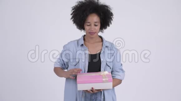 年轻快乐的非洲女人打开礼物盒看上去很惊讶视频的预览图