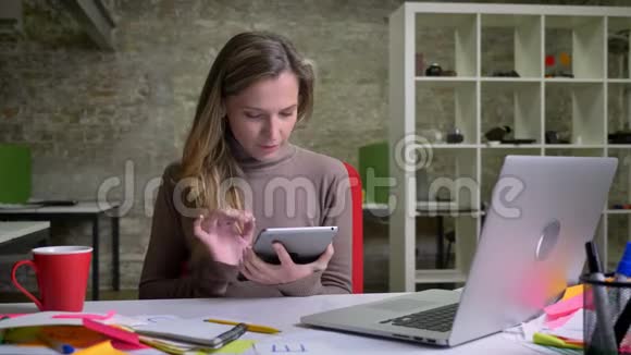 用平板电脑特写白种人漂亮女员工的肖像并在镜头前露出微笑视频的预览图