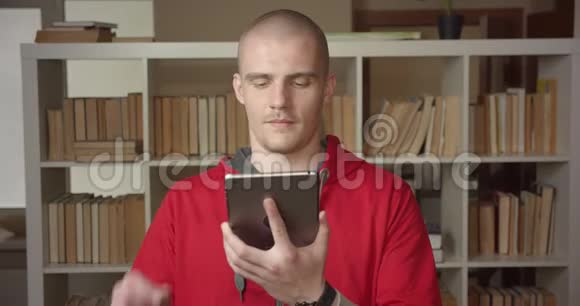 用平板电脑拍摄年轻迷人的白种人男学生的特写肖像并在摄像机上显示绿色彩色屏幕视频的预览图