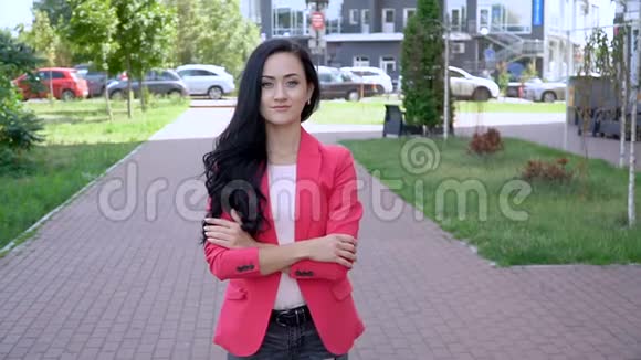 一个穿红色夹克的女人在晴朗的晴天在城市公园里视频的预览图