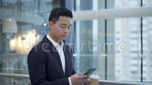 亚洲年轻商人在商务中心喝咖啡拿电话视频的预览图