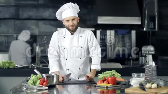 厨师在厨房餐厅开玩笑斯迈利男厨师用刀子摆姿势视频的预览图