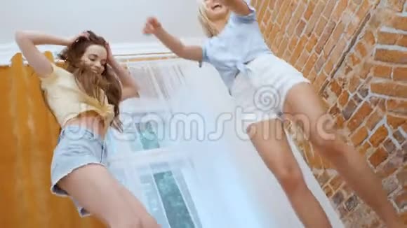 两个年轻快乐的女朋友跳上床玩得很开心视频的预览图