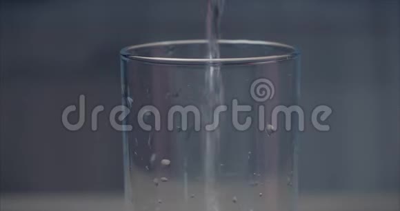 把新鲜的纯净水从瓶子里倒入桌子上的玻璃杯里概念健康视频的预览图