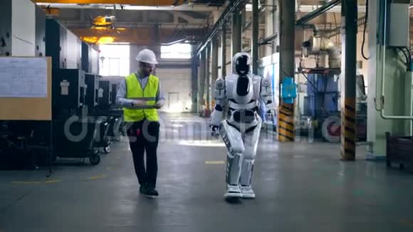 像人一样的半机械人和一名男技术员正在行走视频的预览图