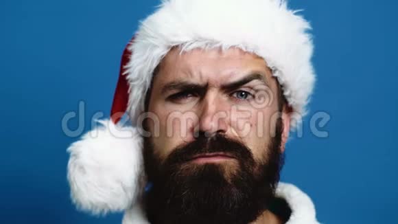 一个戴着新年帽子的留着胡子男人的特写他的眉毛动起来有胡子的男人把眉毛移到蓝色的视频的预览图