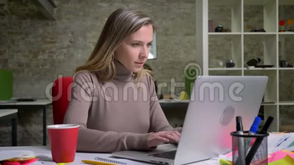 成功的成年女商人在笔记本电脑上打字坐在办公室里享受工作的特写照片视频的预览图