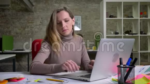 为忙碌的女性办公室工作人员使用笔记本电脑并在工作场所做书面记录做特写视频的预览图