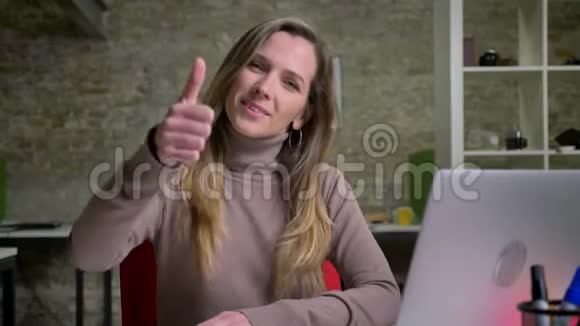 电脑前白种人女办公室工作人员的特写肖像她微笑着挽着她的手臂竖起大拇指视频的预览图