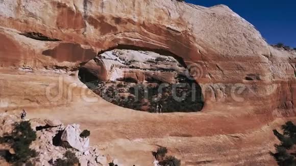 在国家公园保护区的山脉中两名游客在巨大的拱门岩层中飞行视频的预览图