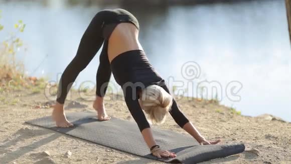 穿着黑色衣服在湖岸做瑜伽的少女视频的预览图