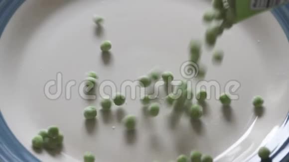 在盘子里从袋子里倒入冰冻的绿色豌豆特写4K冷冻豌豆视频视频的预览图
