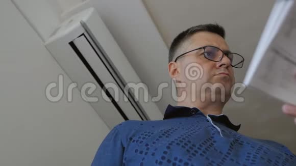 一个戴眼镜的男人拿着遥控器打开家里的空调分离系统连接到视频的预览图