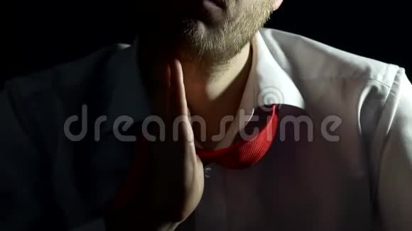 一个穿着白色衬衫带领带留着胡子的男人摸着刮着他的胡子特写黑色背景商人视频的预览图