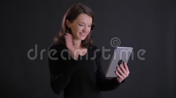 年轻迷人的白种人长发女孩在黑色背景下用平板电脑在视频聊天时微笑的肖像视频的预览图