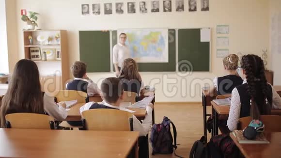 穿着校服的高中生坐在教室里专心听讲座视频的预览图