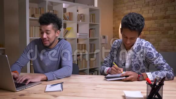 非裔美国和印度男学生一起学习的特写镜头一个是在笔记本电脑上打字另一个是视频的预览图