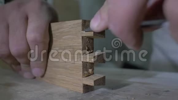 特写一个木匠用凿子在一个木制部分上做一个燕尾在一个工作台上木工加工橡木细节4k4k视频的预览图
