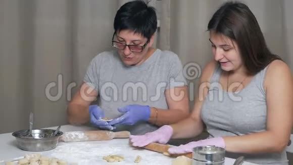 一个怀孕的女孩和她的母亲坐在家里厨房的一张桌子旁午餐准备饺子和肉末卷起来视频的预览图