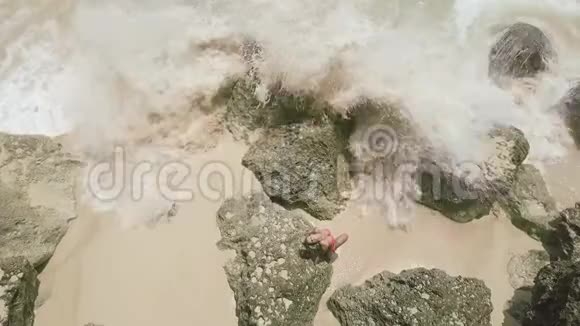 年轻女子穿着比基尼在海边和飞溅的水波空中景观海浪溅起泡沫和浪花视频的预览图