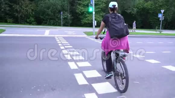 女骑自行车女骑自行车在没有头盔的十字路口行人自行车自行车友好城市视频的预览图