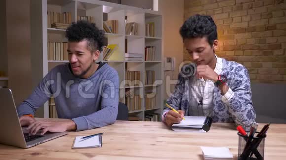 非裔美国和印度男学生合作的特写镜头其中一个是在笔记本电脑上打字视频的预览图