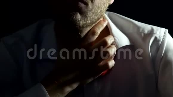 一个留着胡子的人穿着白色衬衫紧张地解开脖子上的领带特写问题背景视频的预览图