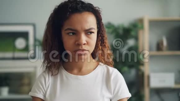 一幅疯狂而愤怒的非裔美国女孩站在家里满脸不高兴皱着眉头看着镜头的肖像视频的预览图