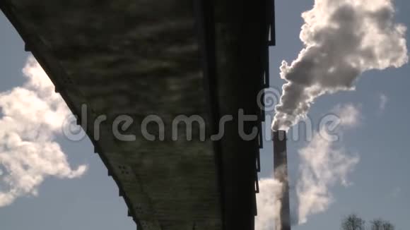 从巨大的工业烟囱升起的烟雾和桥上的太阳水反射视频的预览图