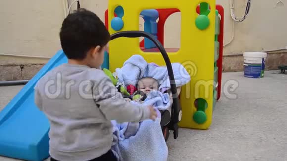 两岁的男孩摇着他的弟弟他坐在汽车座位上玩得很开心视频的预览图