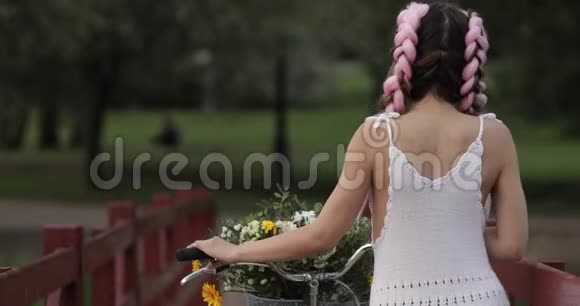 从公园里骑自行车的白衣少女的背影看视频的预览图