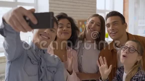 混合种族组5人喜欢在手机摄像头上说话的人青少年们笑着向摄像机问好视频的预览图